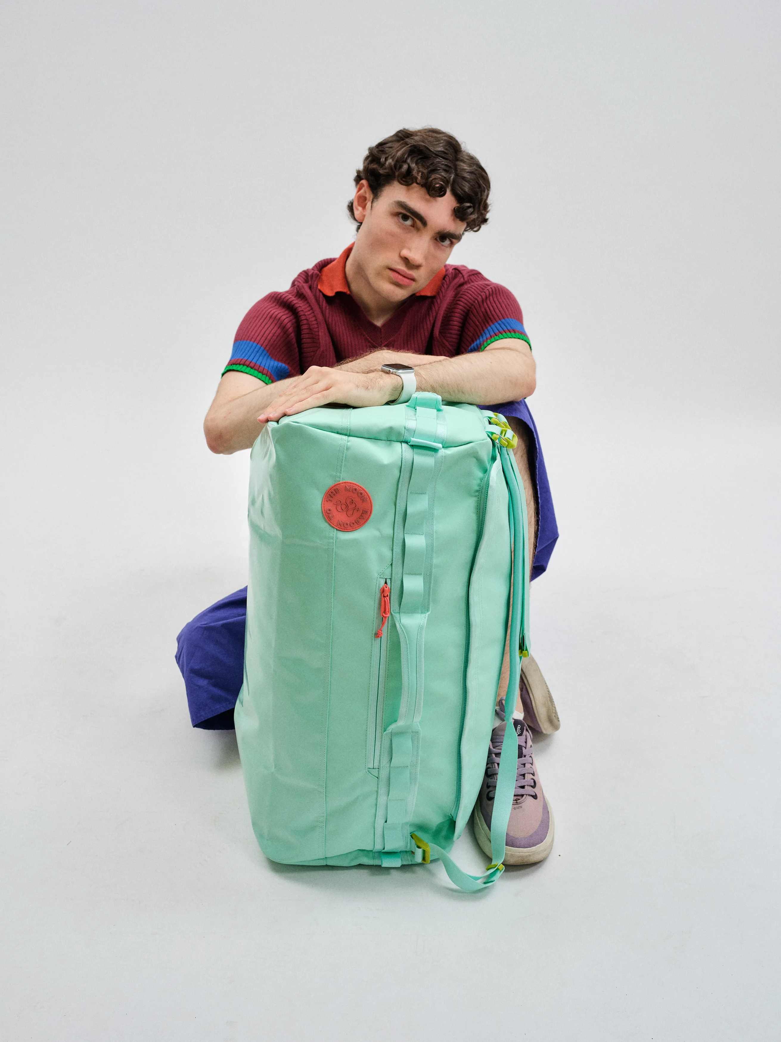 Lachlan looking straight at camera over a turquoise backpack