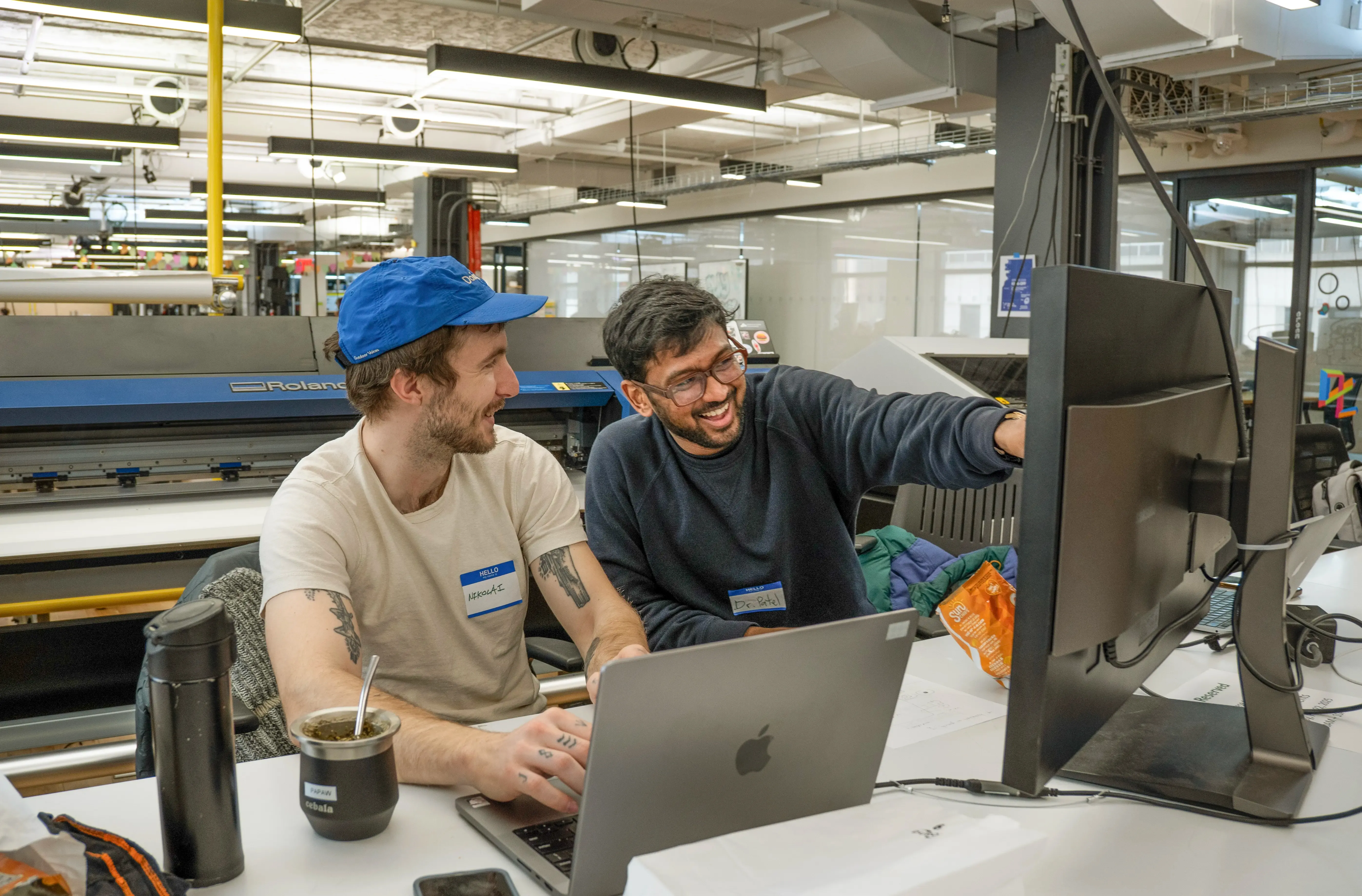 Two people are collaborating on developing a Chrome extension at a desk with laptops