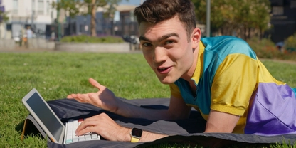 Lachlan smiling outside on a picnic blanket with a Daylight DC-1 tablet