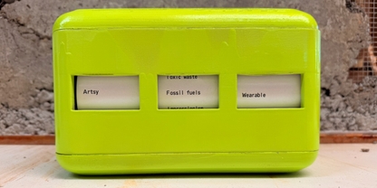 Bright green rounded box with 3 windows saying Artsy Fossil fuels Wearable
